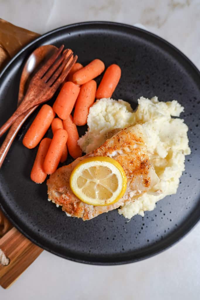 overhead view of plated baked cod with mashed potatoes and carrots