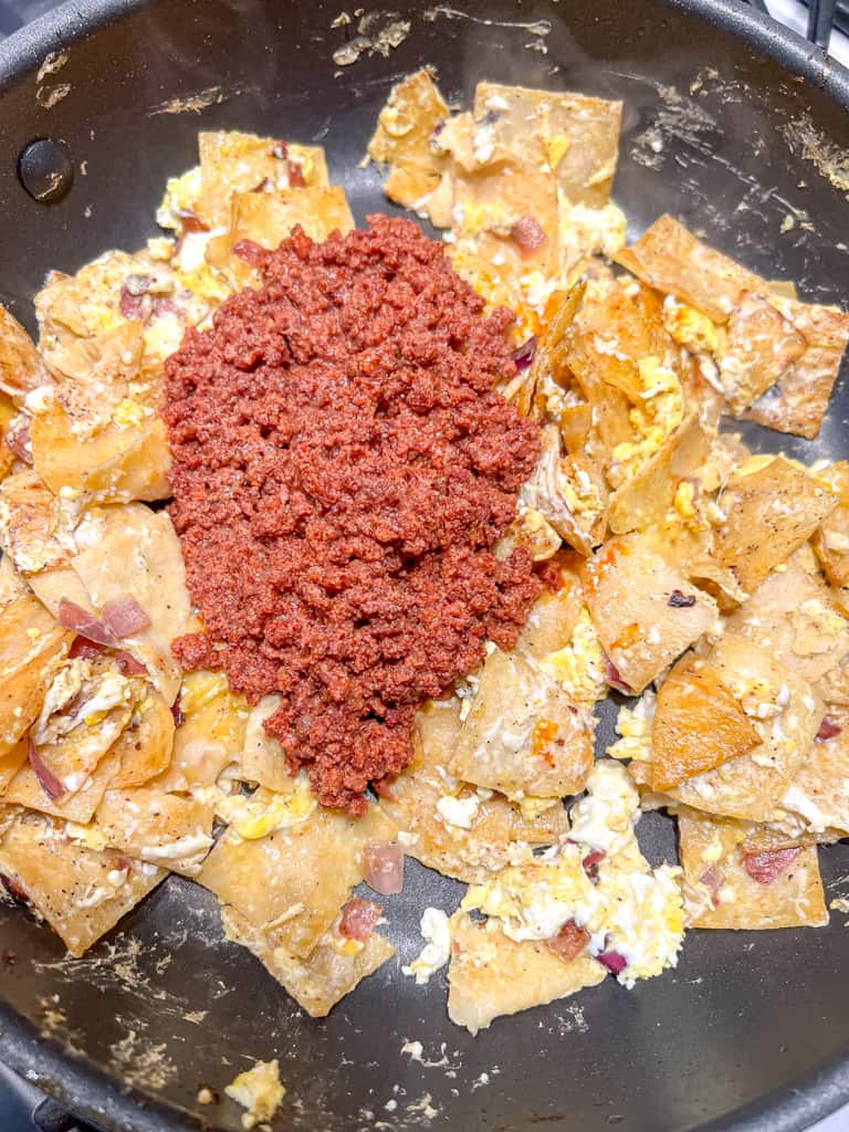 chorizo on top of a skillet full of tortilla chips and eggs