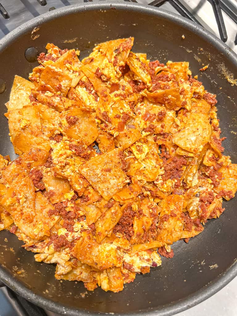 fried tortilla chips combined with scrambled eggs in a skillet
