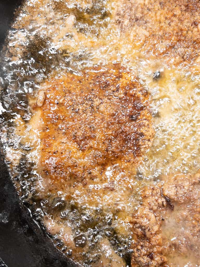 close up view of cube steaks frying in skillet