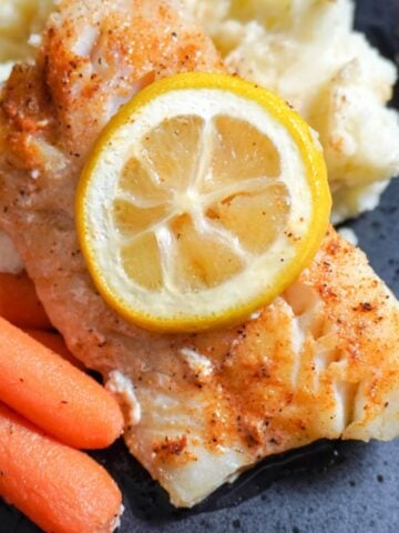 close up view of plated baked cod with mashed potatoes and carrots