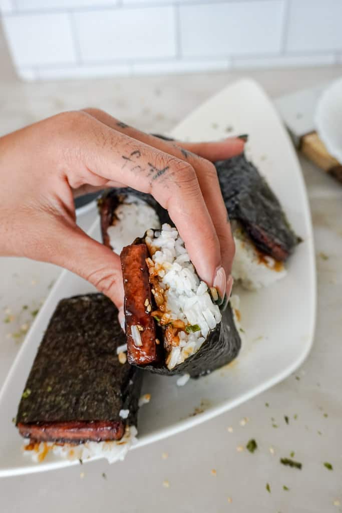 a hand holding a spam musubi