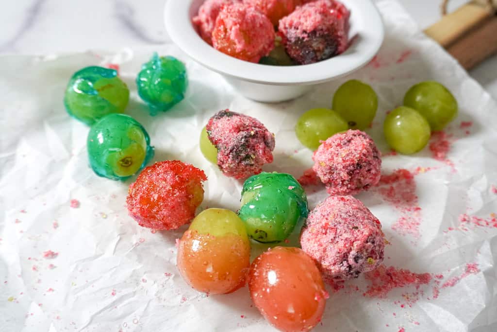 a bowl of candy grapes with scattered grapes surrounding it