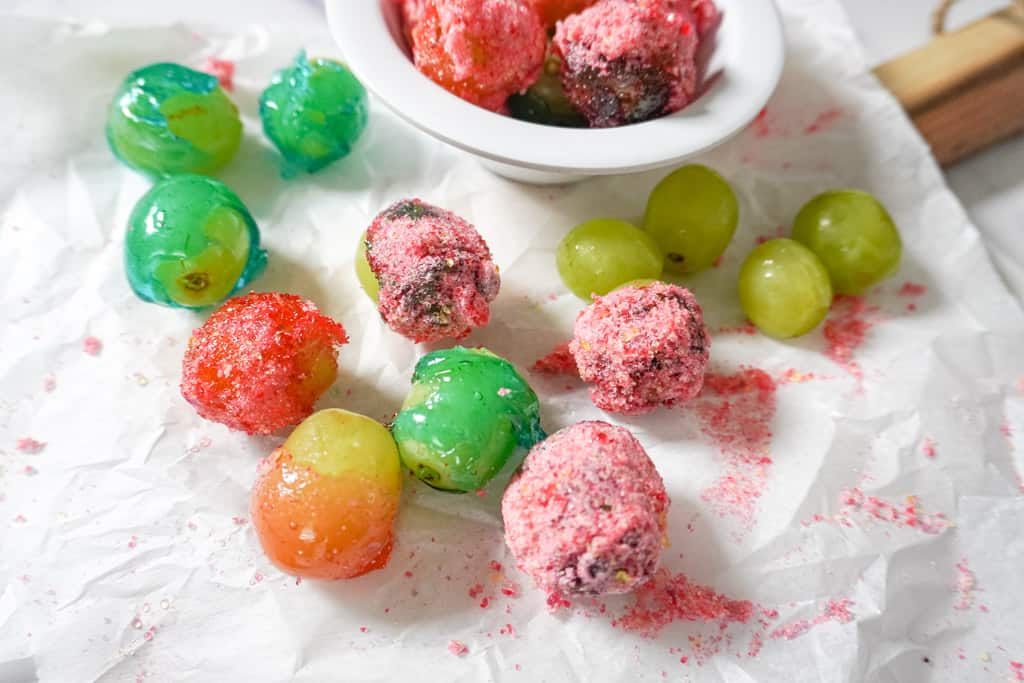 a bowl of candy grapes with scattered grapes surrounding it