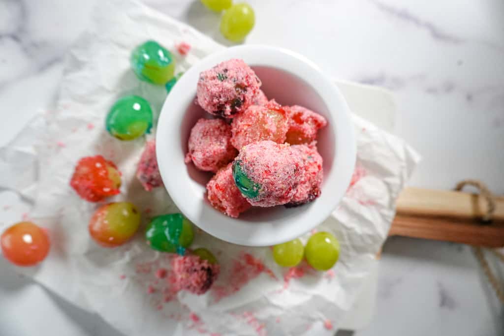 overhhead view of a bowl of candy grapes with scattered grapes surrounding it