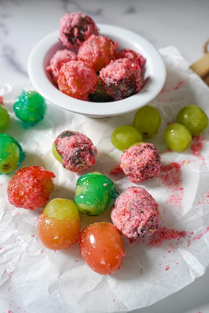 a close up view of a bowl of candy grapes with scattered grapes surrounding it