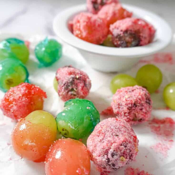 a bowl of candy grapes with scattered grapes surrounding it