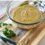 a bowl of grilled chicken marinade on a cutting board with a spoon beside it