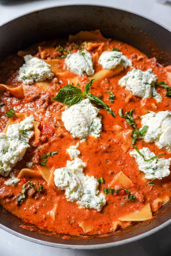 a pot full of skillet lasagna topped with ricotta
