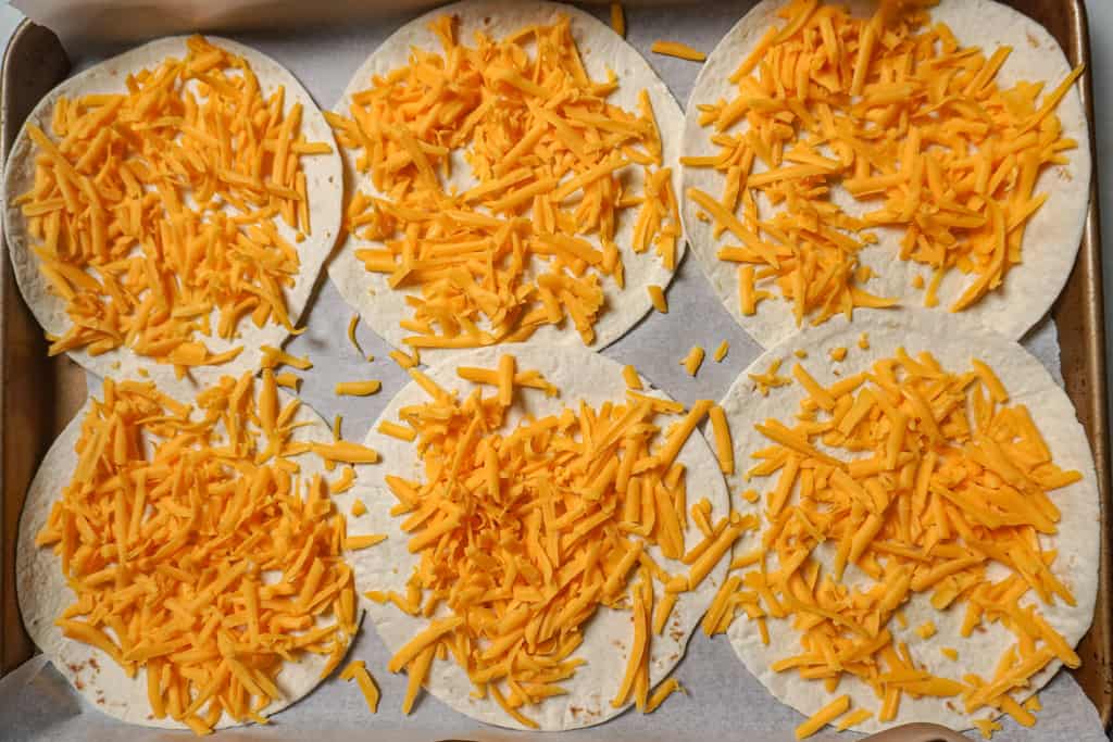 shredded cheddar cheese on tortillas
