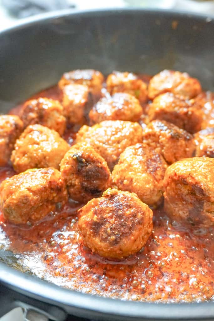 meatballs cooking in sauce in a pan