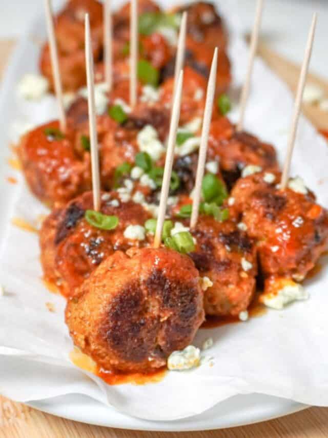 buffalo chicken meatballs on a platter with buffalo sauce in the background