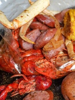 crawfish, crab legs, shrimp, corn on the cob, and potatoes all cooked in a seafood boil bag with a delicious sauce