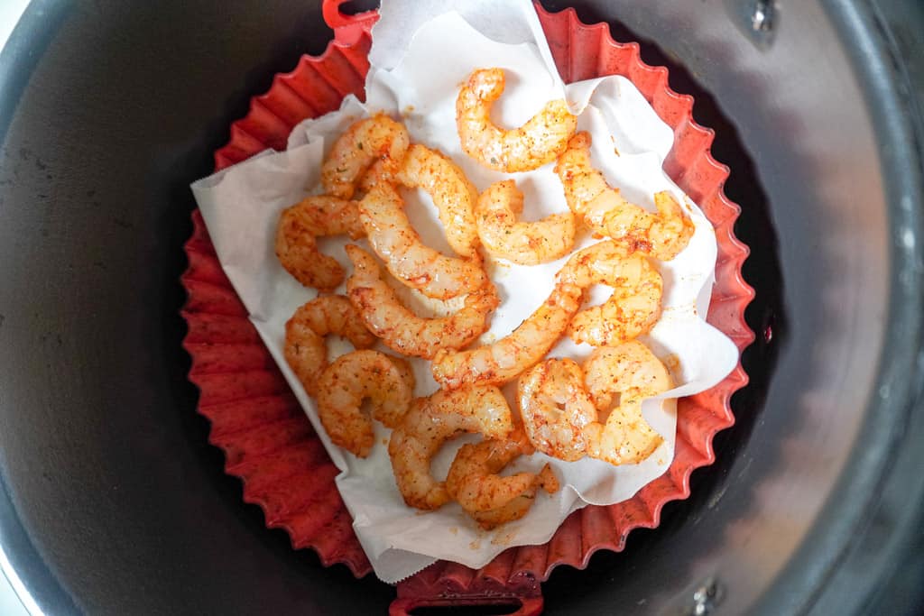 overhead view of raw reasoned shrimp in an air fryer basket