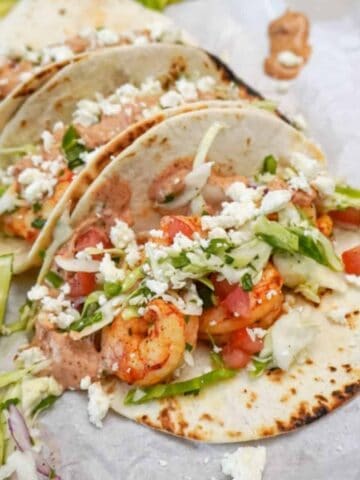 shrimp tacos setting on a platter with a side of lime wedges