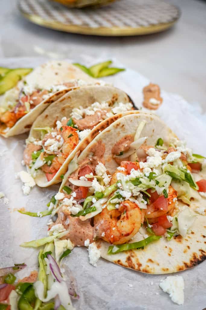 shrimp tacos sitting on a platter with cabbage slaw and other toppings