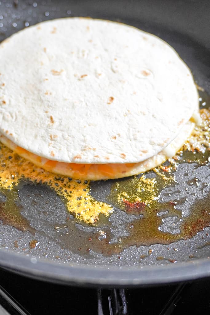 two flour tortillas with cheese in the middle cooking on a skillet