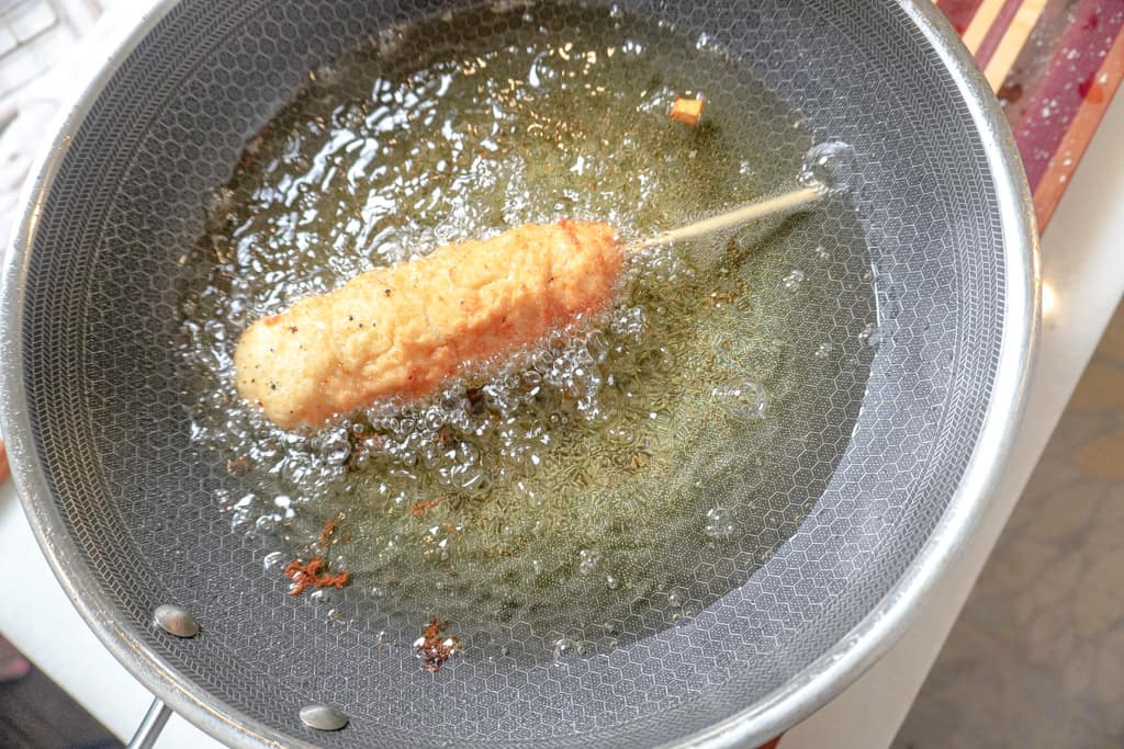 nearly done korean corn dog frying in skillet