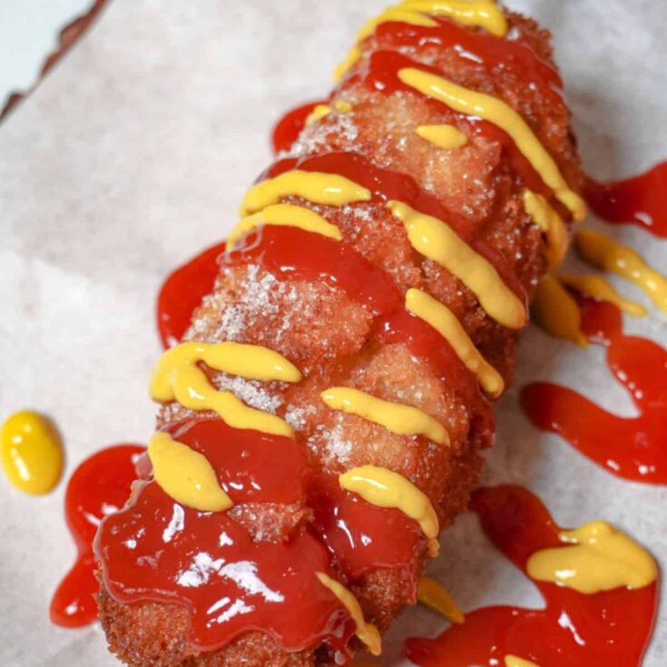 close up view of Korean corn dogs drizzled with ketchup and mustard
