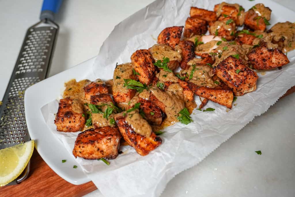 plated salmon bites with cajun garlic butter with a grater and lemon wedge on the side