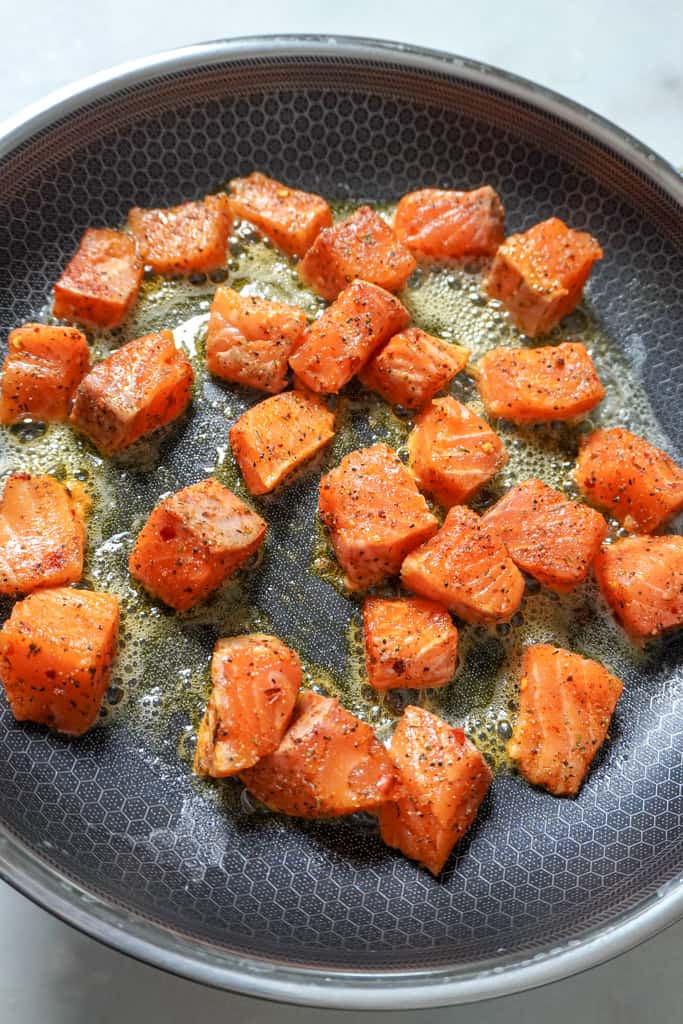 salmon bites frying in a skillet