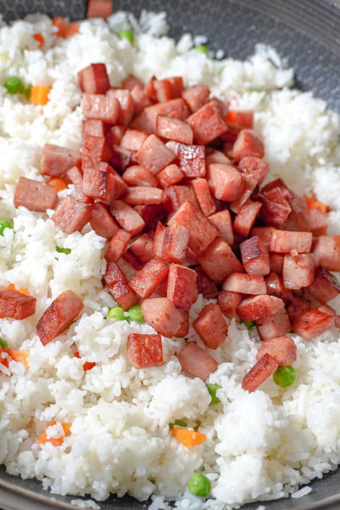 cooked spam cubes added to white rice with peas and carrots