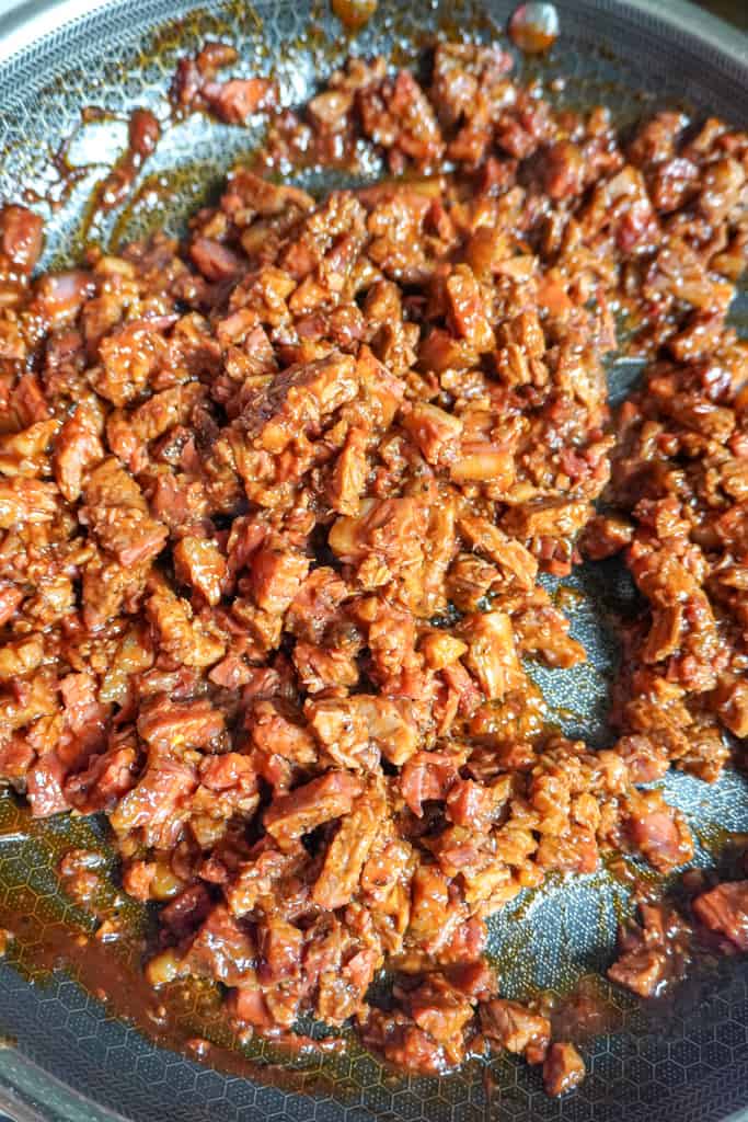 brisket tossed in a sauce in a skillet