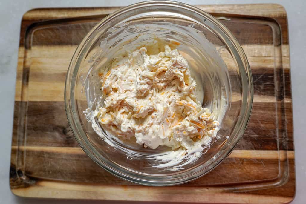 overhead view of cream cheese and cheddar mixture in a clear bowl