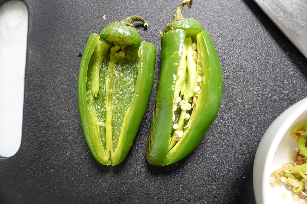 close up view of two sliced jalapeños during the process of being deseeded