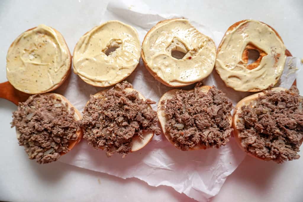 assembled steak egg and cheese bagels with the cheese not yet added