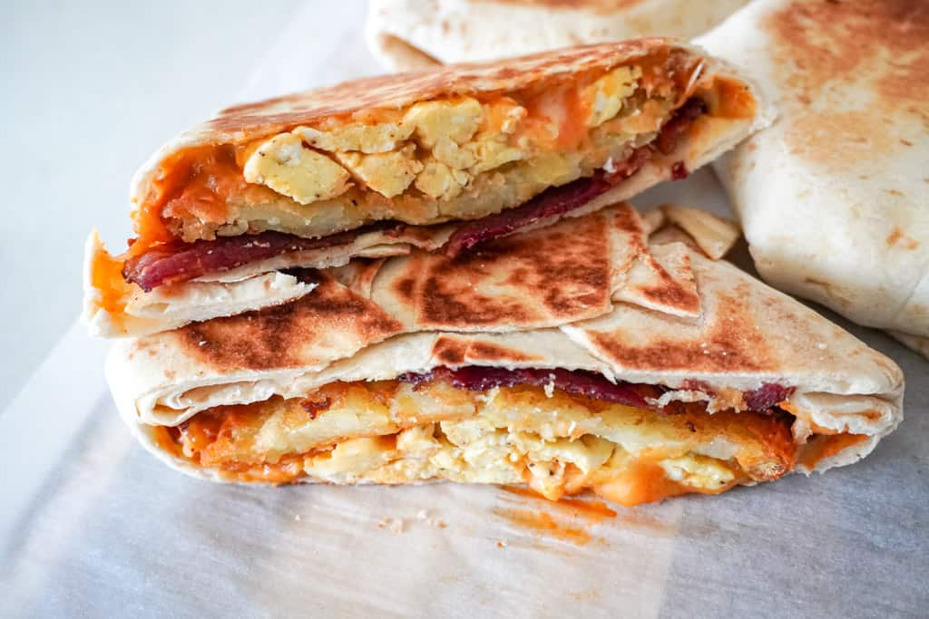 a close up view of a breakfast crunchwrap sliced in half and stacked