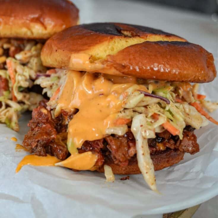 close up view of a brisket sandwich with coleslaw and sauce
