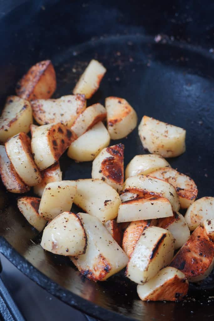 browned potatoes pushed to one side of a skillet