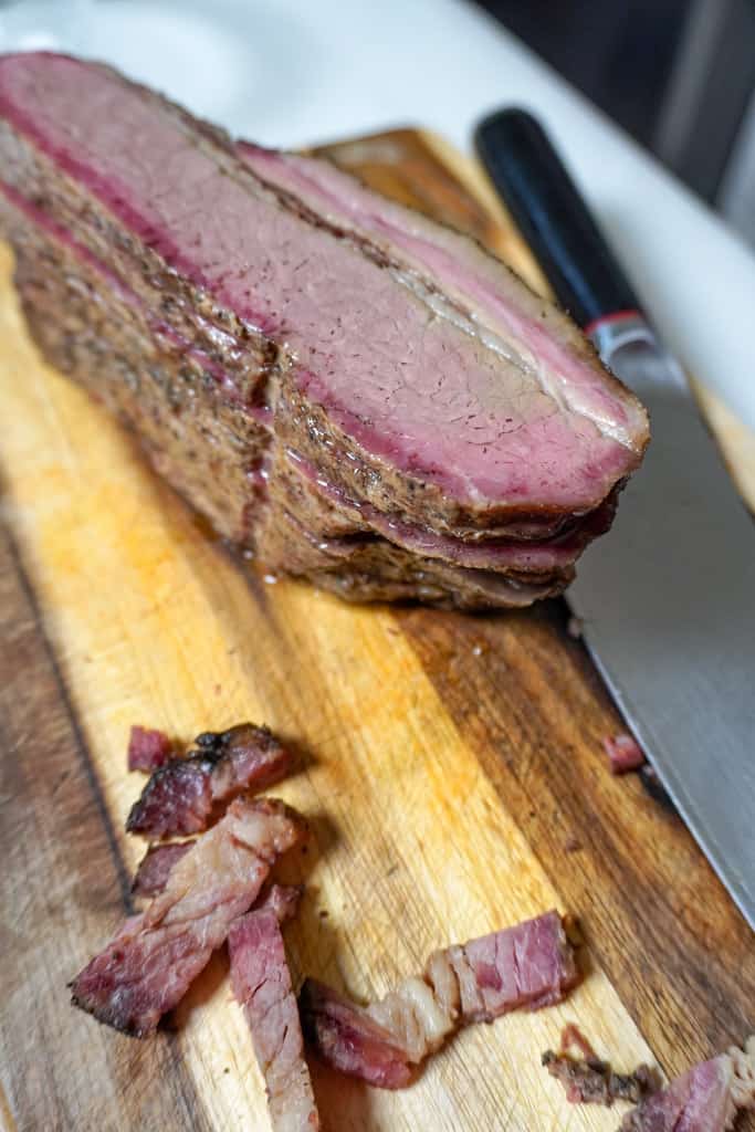 a slab of brisket on a cutting board next to a knife