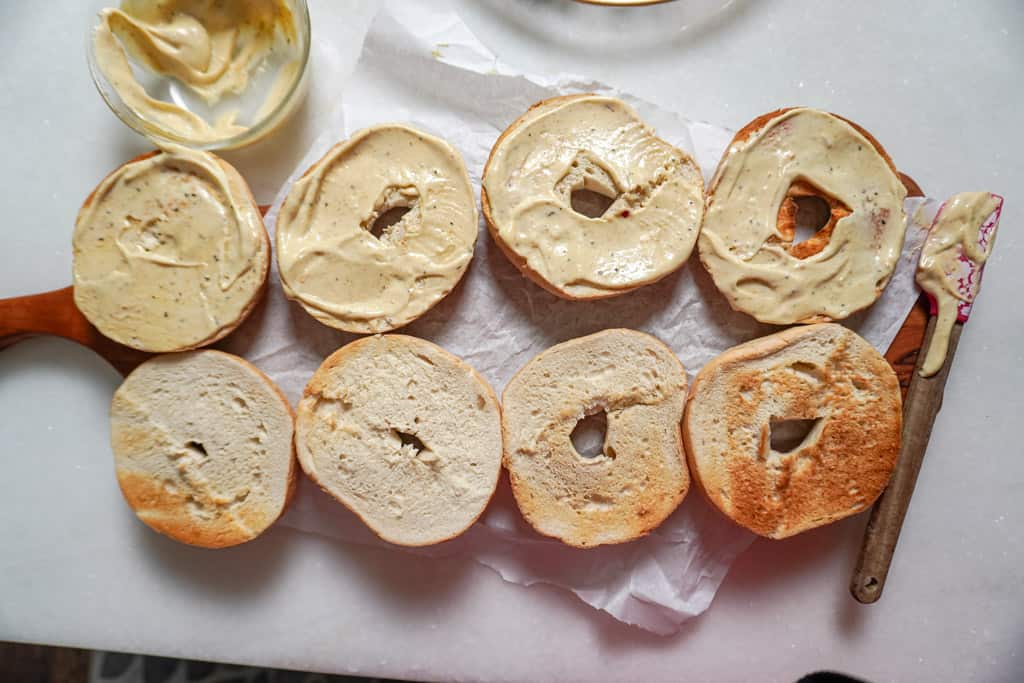 overhead view of sliced bagels with sauce slathered on half the slices
