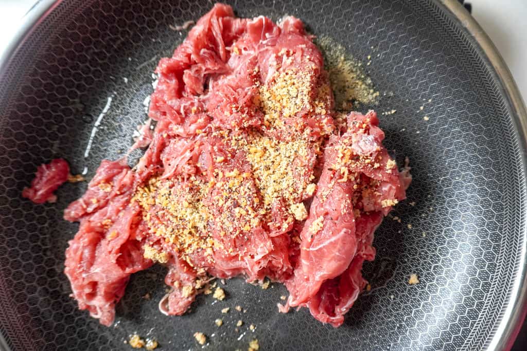 raw seasoned steak in a skillet