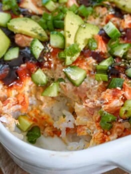 a casserole dish full of salmon sushi bake with a corner piece scooped out