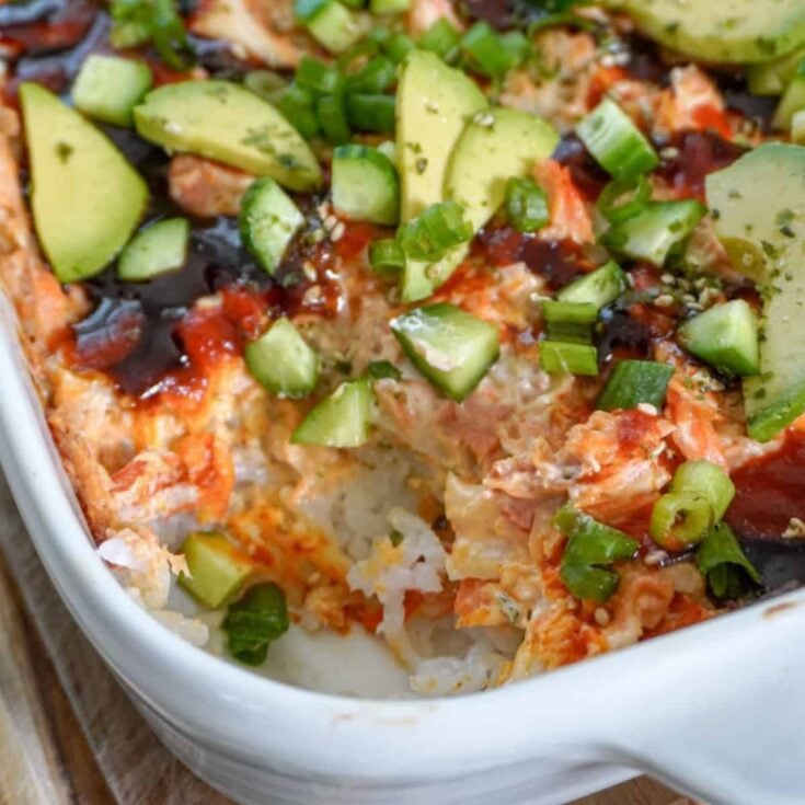 a casserole dish full of salmon sushi bake with a corner piece scooped out