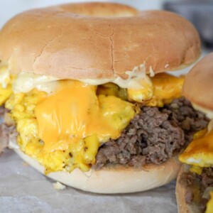 close up view of steak egg and cheese bagel with melty cheese on top of eggs and shaved steak