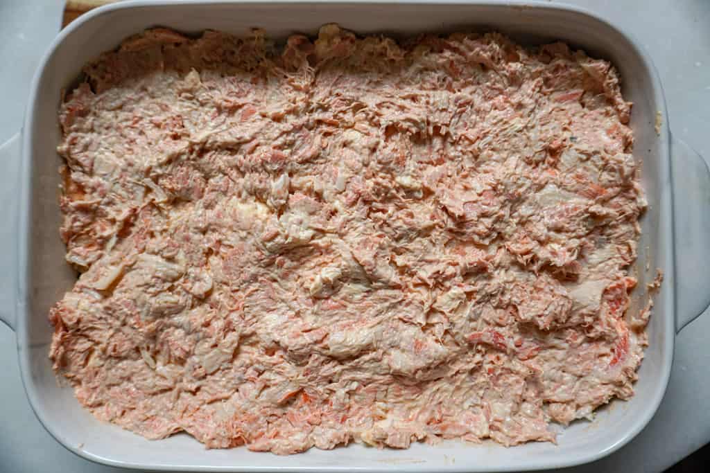 a layer of salmon and crab mixture spread in a casserole dish