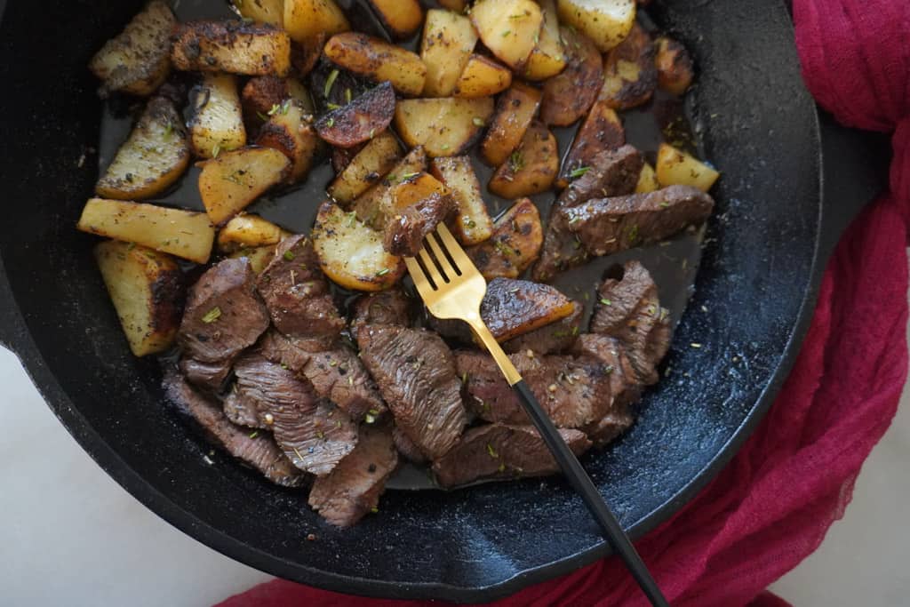 skillet steak and potatoes with a fork inserted
