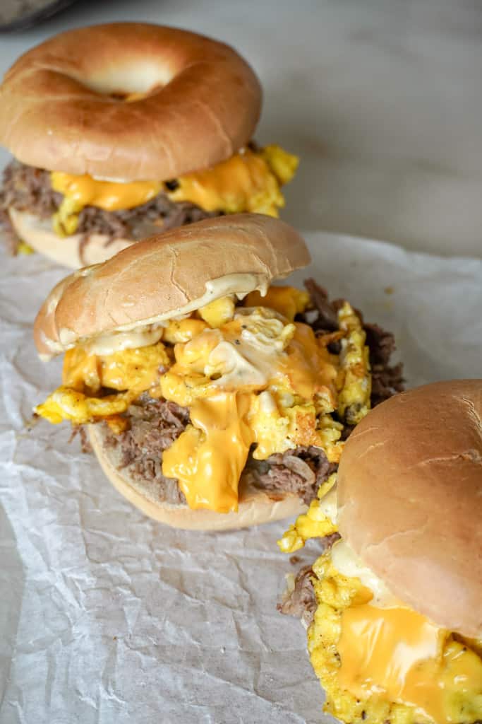 three steak egg and cheese bagel with the center bagel open to reveal the contents