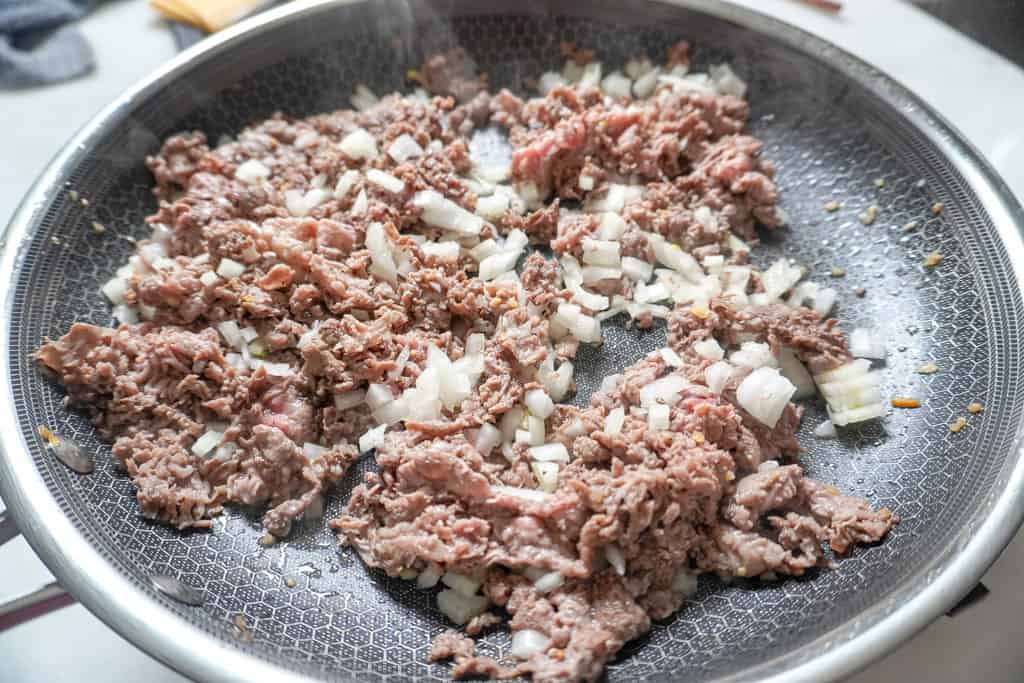 steak and onions frying in a skillet