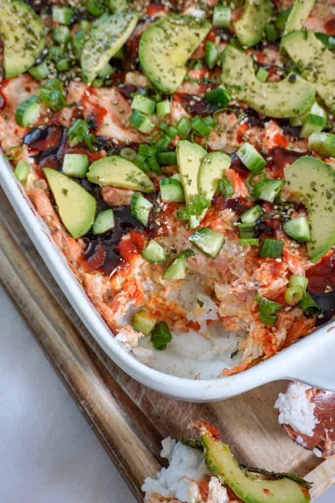 a casserole dish full of salmon sushi bake with a corner piece scooped out