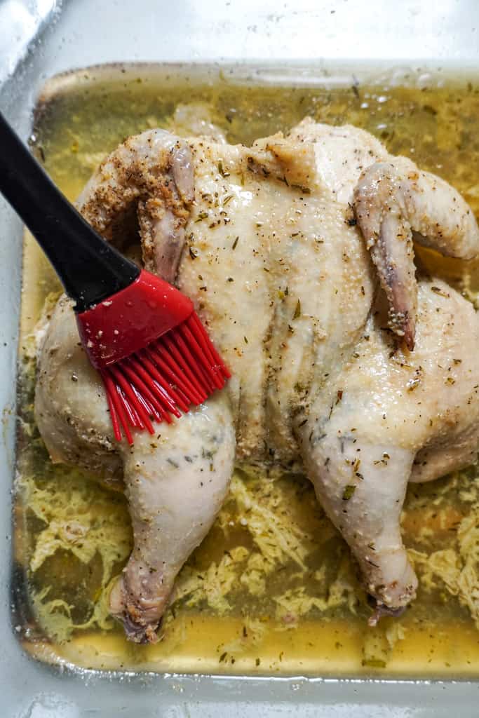 a baster applying garlic butter to spatchocked cornish hen