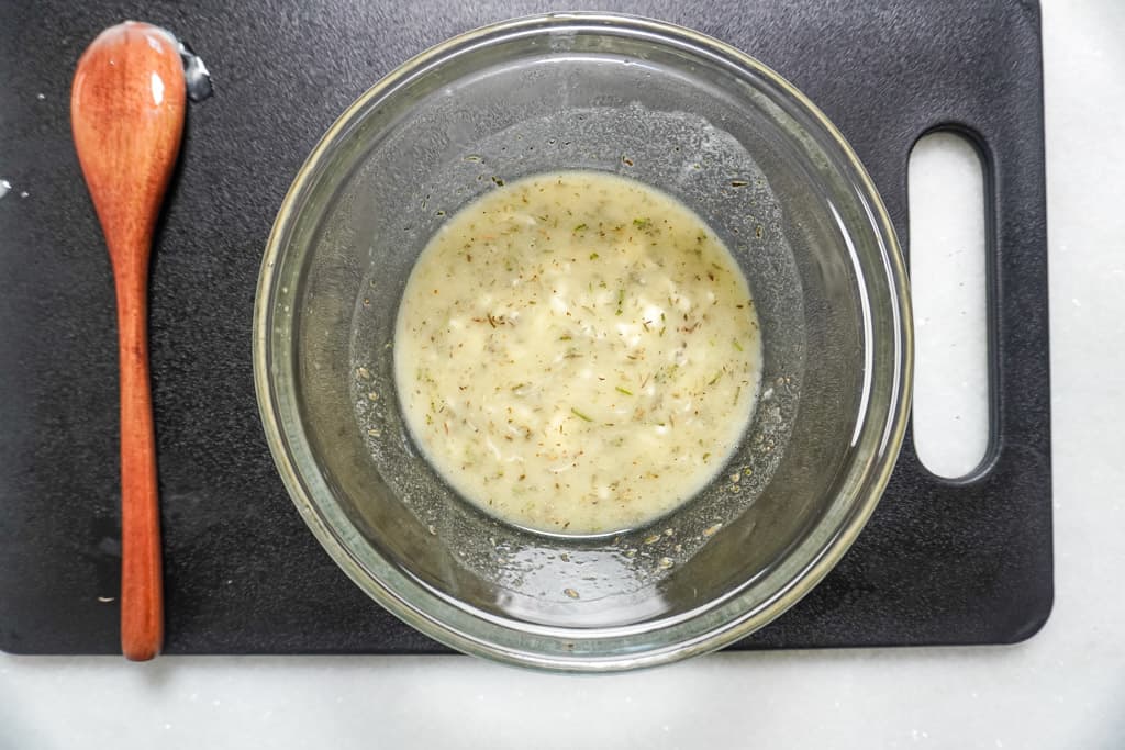 herb butter in a bowl on a cutting board next to a wooden spoon