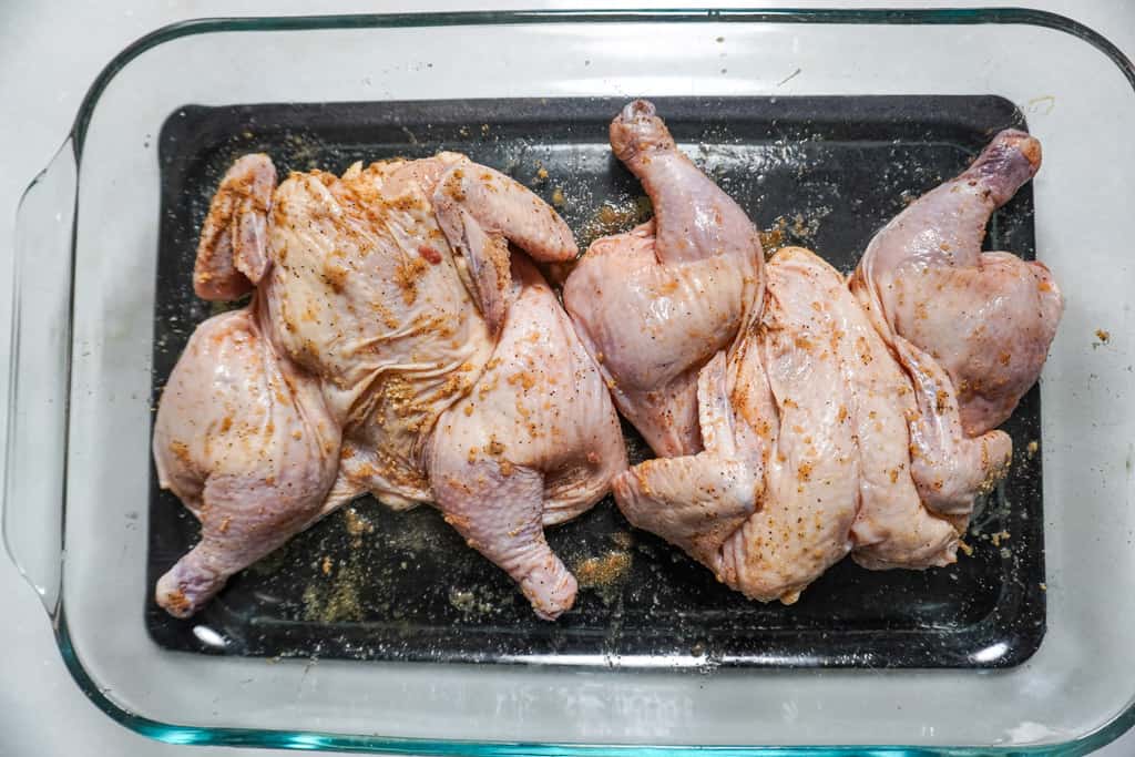 seasoned full chickens in baking pan before cooked