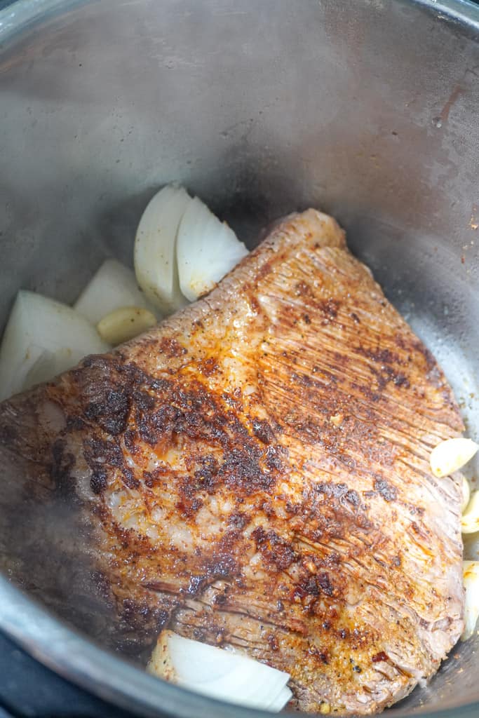seasoned brisket in an instant pot with onions