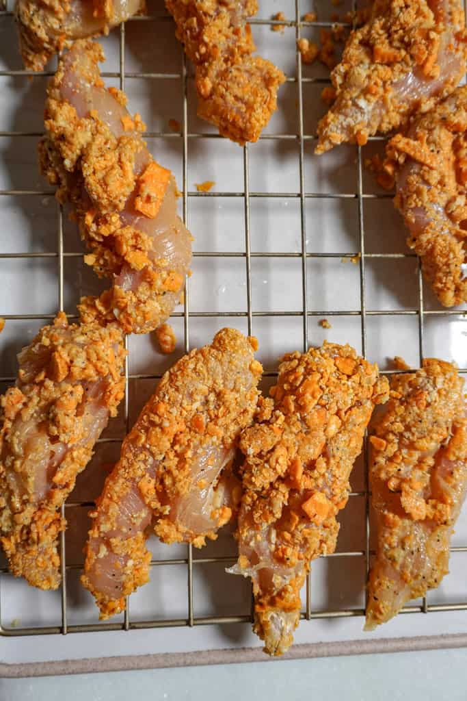 raw breaded chicken tenders on a cooling rack