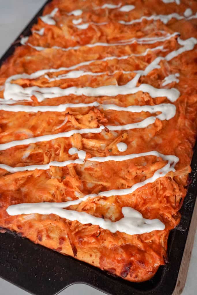 sheet pan buffalo chicken pizza drizzled with ranch dressing
